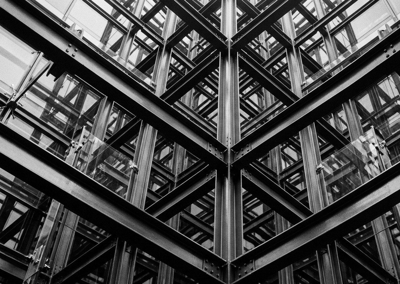 Black-and-white view up through an exposed steel and glass structural frame.